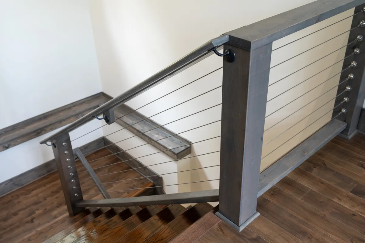 A welcoming mudroom area with stylish wooden stairs and metal accents, offering a practical spot for guests to drop off hiking shoes or ski gear. The entryway feels modern yet warm, setting the tone for mountain adventures and easy transitions from outdoors to in.