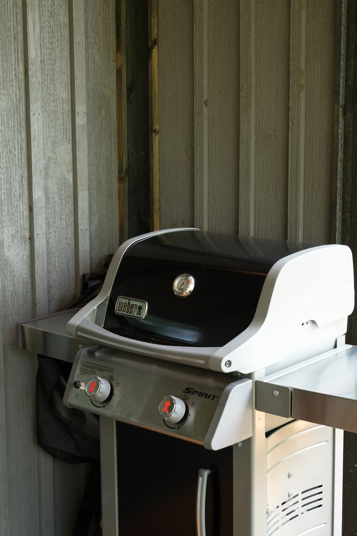 An upscale indoor grilling area featuring a modern grill, metal surfaces, and wooden walls, designed for relaxed, communal barbecuing. The space is welcoming and encourages group gatherings and shared meals.