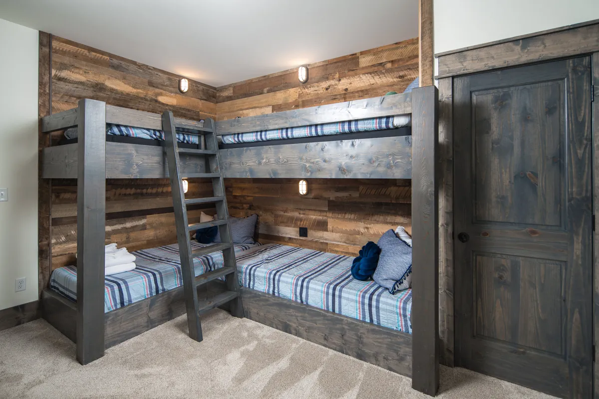 A custom bunk room with sturdy wooden bunk beds, a ladder for easy access, and a warm, inviting ambiance. The playful layout encourages sleepovers and shared experiences, ideal for kids and teens. The space is cozy yet practical, supporting family togetherness.
