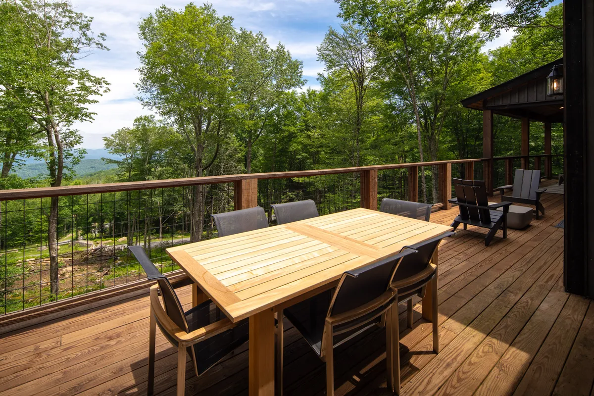 A spacious outdoor dining area featuring a wooden table surrounded by greenery with a breathtaking mountain view in the background. The serene setting is ideal for family gatherings, morning coffee, and evening relaxation while immersed in nature.